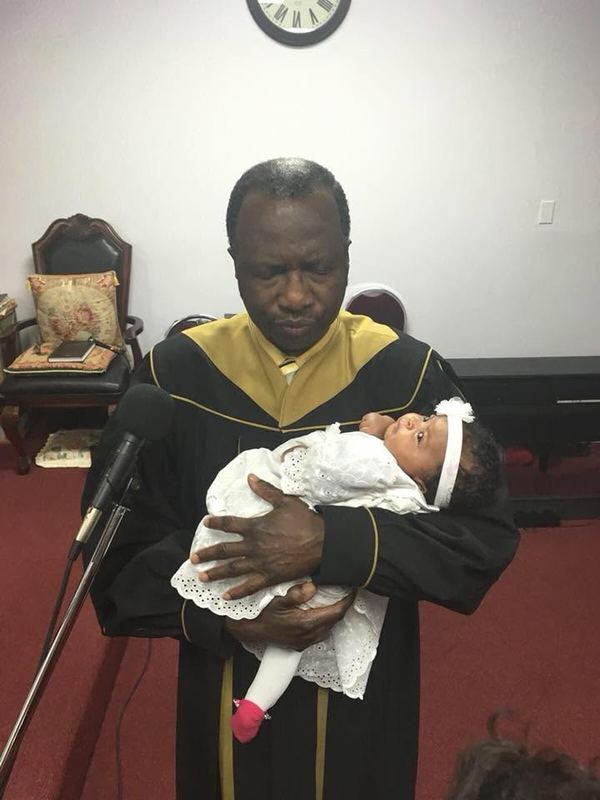 Bishop Wallace holding a baby during a dedication